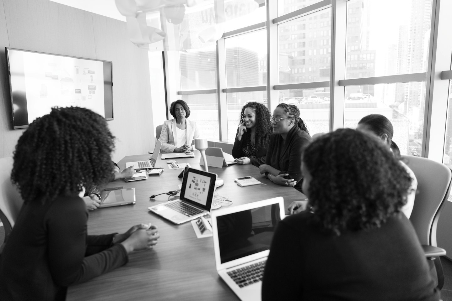 Schwarze Frauen arbeiten mit Laptops an einem Konferenztisch zusammen.